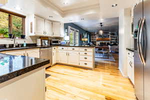 Kitchen featuring white cabinetry, kitchen peninsula, a healthy amount of sunlight, and stainless steel appliances