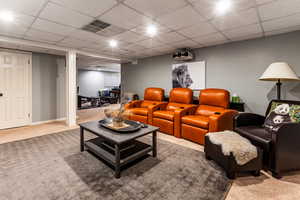 Carpeted cinema room with a paneled ceiling