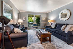 Living room featuring a textured ceiling, light carpet, and ornamental molding