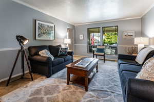 Living room with carpet flooring, a textured ceiling, and crown molding