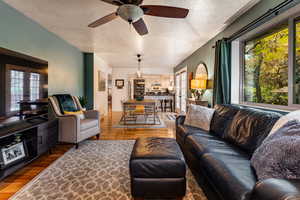 Living room with ceiling fan, a textured ceiling, and dark hardwood / wood-style floors