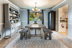 Dining room with light hardwood / wood-style floors, a chandelier, a textured ceiling, and ornamental molding