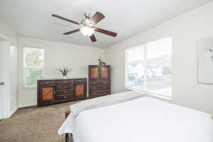 Carpeted bedroom with multiple windows and ceiling fan