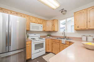 Kitchen featuring light brown cabinetry, tile patterned flooring, sink, and white appliances