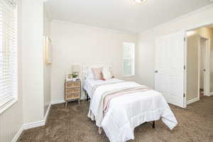 Bedroom with ornamental molding and dark colored carpet