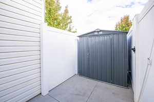 View of gate featuring a patio and a storage unit