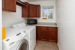 Laundry room featuring washer and clothes dryer, and cabinets