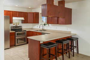 Kitchen with kitchen peninsula, a sink, and appliances with stainless steel finishes