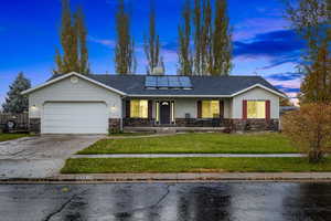 Ranch-style house with a garage, porch, and solar panels