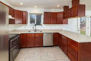 Kitchen featuring kitchen peninsula, stainless steel appliances, sink, and light tile patterned flooring