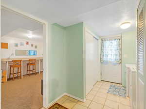 Foyer entrance featuring a textured ceiling and light colored carpet