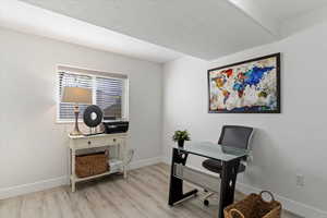 Office area with a textured ceiling and light wood-type flooring