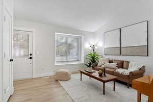 Living room with vaulted ceiling and light hardwood / wood-style floors