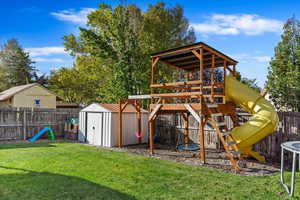 View of play area with a lawn and a storage shed