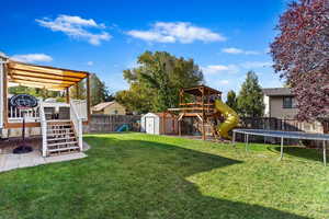 View of yard with a storage unit, a playground, and a trampoline