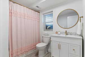 Full bathroom with shower / bath combo with shower curtain, vanity, hardwood / wood-style flooring, and toilet