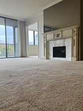 Unfurnished living room with a premium gas fireplace, carpet floors, and ornamental molding