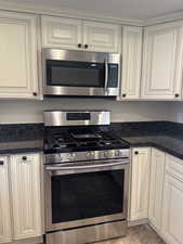 Kitchen with dark stone counters and appliances with stainless steel finishes