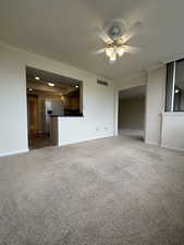 Unfurnished living room with ceiling fan, carpet, and ornamental molding