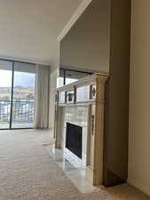 Unfurnished living room with light colored carpet, a mountain view, a premium fireplace, and crown molding