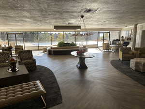 Living room with wood-type flooring, a notable chandelier, and a textured ceiling