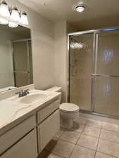 Guest Bathroom featuring toilet, vanity, tile  floors, and a shower with door