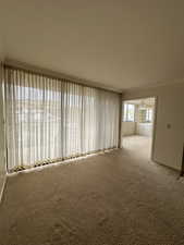 Carpeted spare room with ceiling fan and crown molding