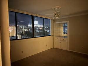 Carpeted spare room featuring ceiling fan and ornamental molding