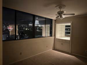 Carpeted empty room featuring crown molding and ceiling fan