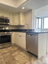 Kitchen with kitchen peninsula, appliances with stainless steel finishes, sink, and ornamental molding