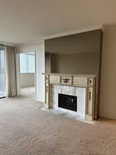 Unfurnished living room with light carpet, ornamental molding, and a fireplace