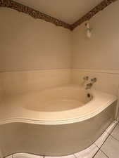 Primary Bathroom garden tub with heat lamp, tile flooring and tiled tub