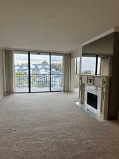 Unfurnished living room featuring a premium fireplace, light colored carpet, and a wealth of natural light