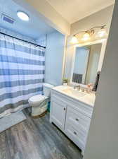 Bathroom with toilet, vanity, wood-type flooring, and a textured ceiling