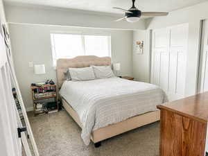 Bedroom featuring a textured ceiling, light carpet, ceiling fan, and a closet