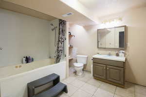 Full bathroom featuring tile patterned floors, vanity, toilet, and shower / bathtub combination with curtain