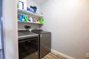 Washroom with light wood-type flooring and washing machine and clothes dryer