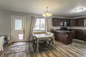 Kitchen with hardwood / wood-style floors, pendant lighting, an inviting chandelier, black electric range, and dark brown cabinetry