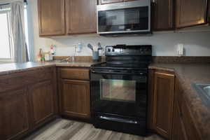 Kitchen featuring dark brown cabinets, light hardwood / wood-style floors, and black range with electric cooktop