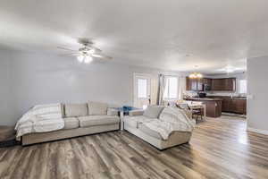 Living room featuring dark wood-type flooring and ceiling fan with notable chandelier