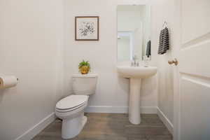 Bathroom featuring wood-type flooring, toilet, and sink