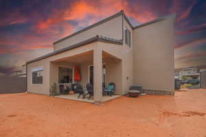 Back house at dusk featuring central AC unit and a patio