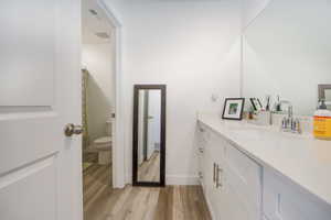 Bathroom with hardwood / wood-style floors, vanity, and toilet