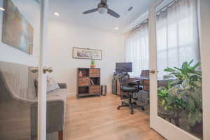 Home office featuring ceiling fan, french doors, and light hardwood / wood-style floors