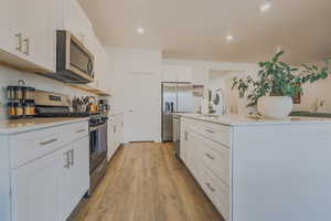 Kitchen with white cabinetry, sink, light hardwood / wood-style flooring, and appliances with stainless steel finishes