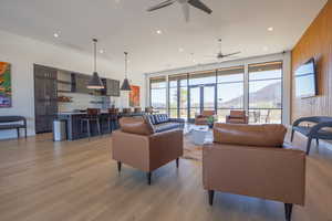 Living room featuring light wood-type flooring, wooden walls, and ceiling fan