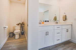 Bathroom featuring hardwood / wood-style floors, vanity, and toilet