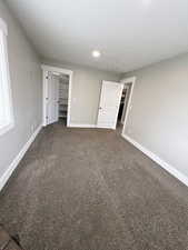 Unfurnished bedroom with a closet and dark carpet