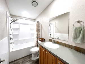 Full bathroom featuring hardwood / wood-style flooring, vanity, toilet, and shower / bathtub combination with curtain