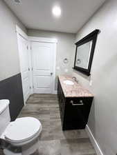 Bathroom with tile walls, hardwood / wood-style floors, vanity, and toilet